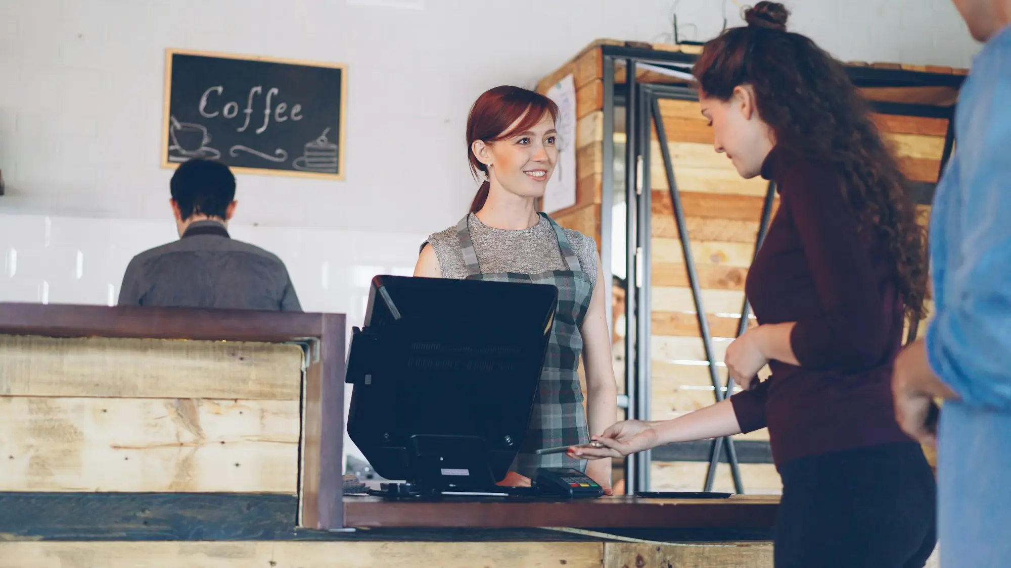 Cafe owner training a new staff member at the counter